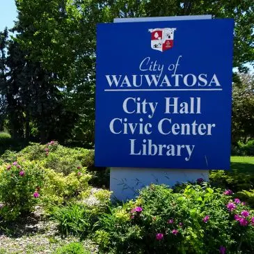 Sign for City of Wauwatosa, indicating City Hall, Civic Center, and Library. Surrounded by landscaping.