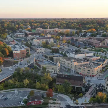 Aerial view of a small town with autumn foliage, featuring buildings, streets, and a river.