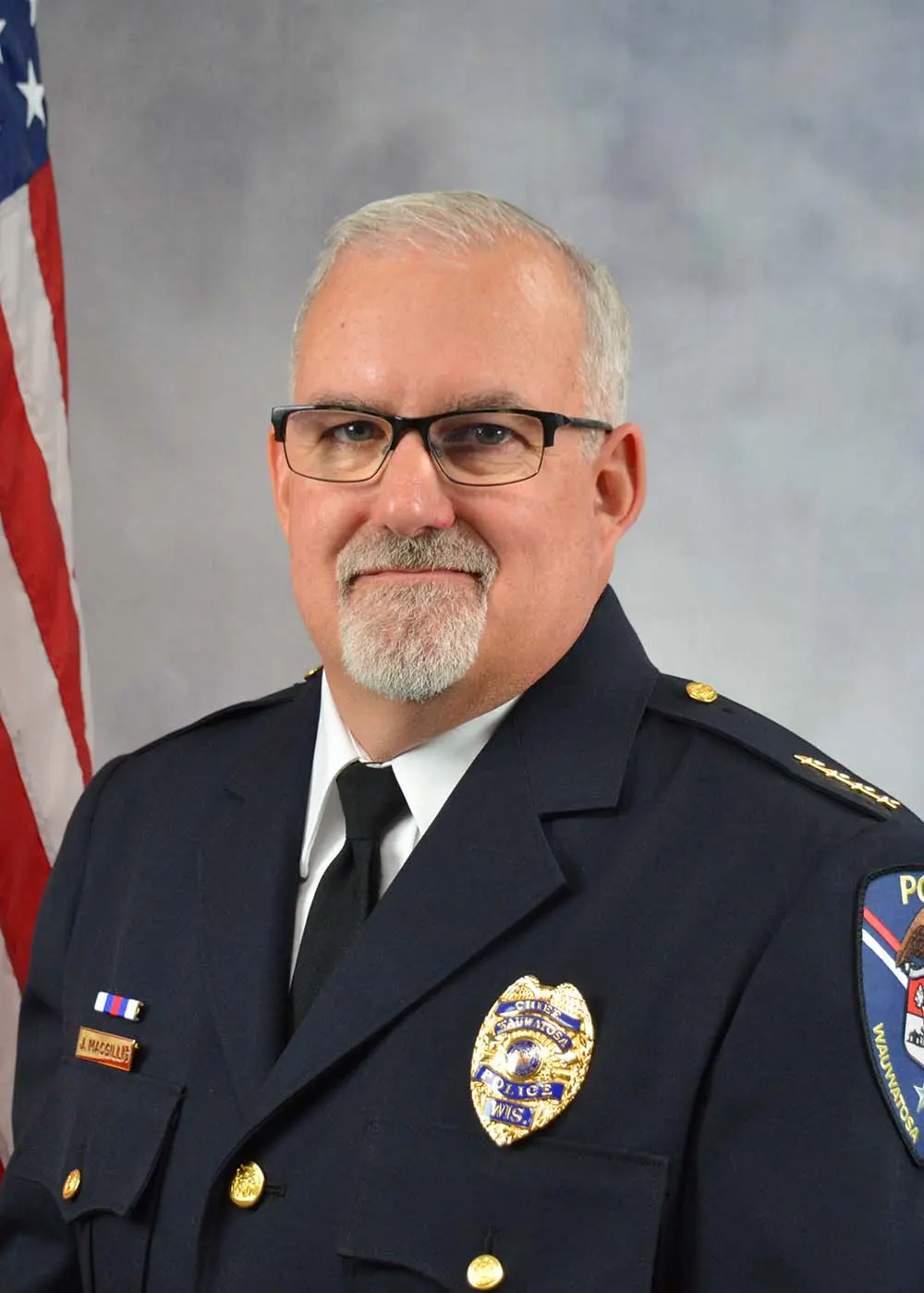 Wauwatosa Police Chief A. Massignano in uniform, with American flag in background.