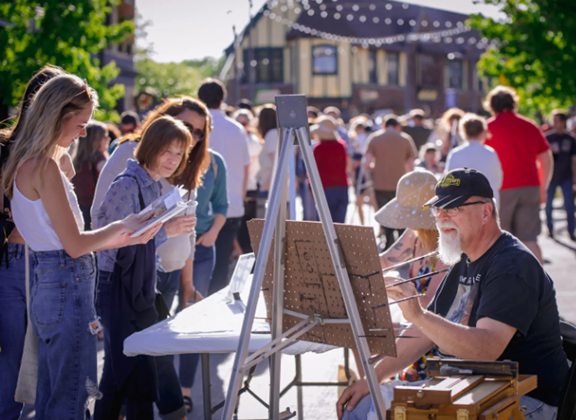 An artist paints outdoors while onlookers observe.