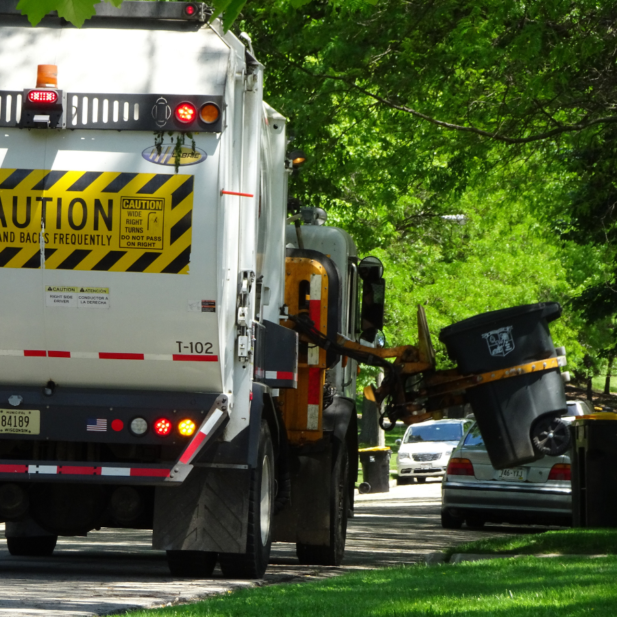 Rear view of a Public Works garbage truck with a bin being lifted.